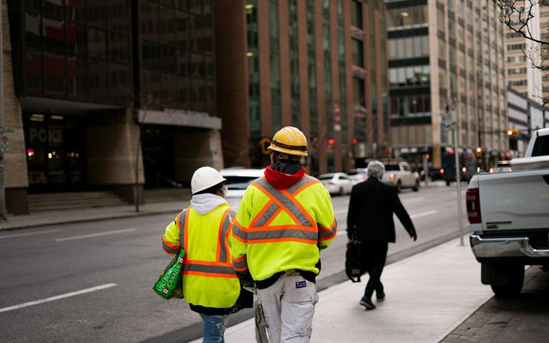 Two people in hi-vis vests outside commercial buildings